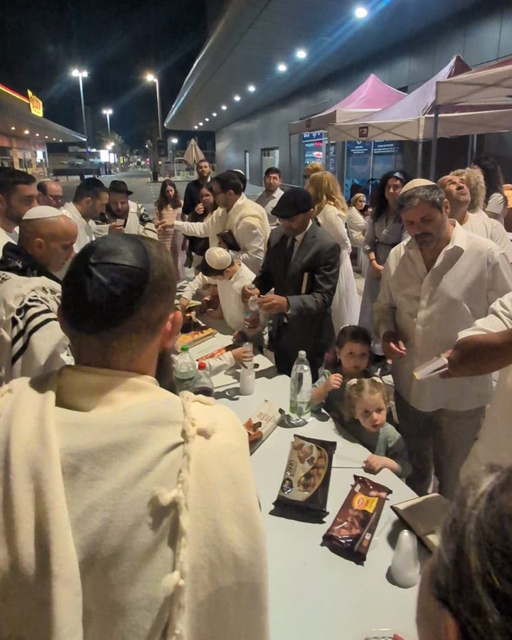 הקהילה מתכנסת בערב סביב שולחן כיבוד ברחוב, ליד בית חב״ד רובע לכיש